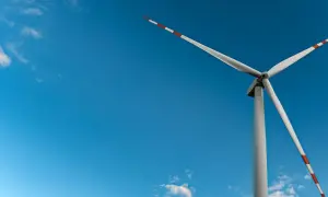 Wiatrak na tle błękitnego nieba, symbol czystej energii wiatru.