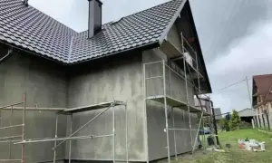 Dom w trakcie prac elewacyjnych, rusztowania wokół, szara ściana. Sprawdzamy elewacja cena za m2 robocizna.