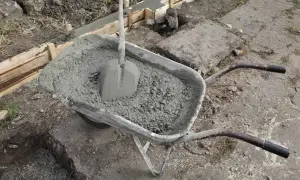 Taczka z betonem i łopatą czeka na wylanie fundamentów. Uziom fundamentowy w trakcie budowy.