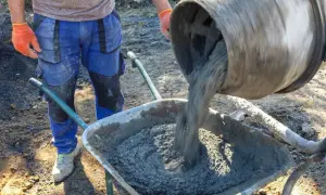 Robotnik wylewa beton B25 z betoniarki do taczki. Sprawdzamy beton B25 cena za m3.