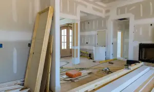 Wnętrze w trakcie przebudowy, widoczne drzwi, materiały budowlane i narzędzia.