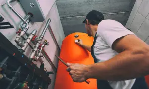 Technik sprawdza temperaturę na bojlerze, który jest częścią systemu ogrzewania gazowego.