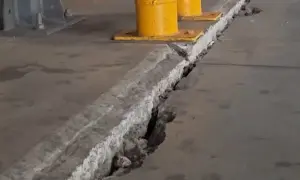 Pęknięcie w betonowej posadzce z widocznymi podporami przemysłowymi w tle.