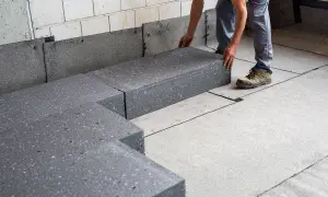 Budowlaniec układa płyty styrobetonu na dachu.