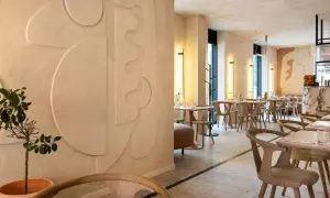 Nowoczesne wnętrze restauracji z dekoracyjnymi tynkami glinianymi na ścianach, geometrycznymi formami i minimalistycznymi meblami.