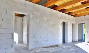 Wnętrze domu w budowie, ściany z bloczków suporeks, widoczne drewniane krokwie dachu.