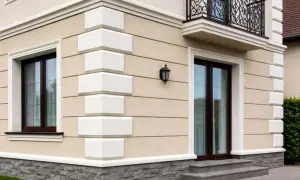 Elegancka fasada domu z kamiennym cokołem i białymi boniami. Okna i drzwi w ciemnej oprawie.