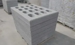 Stos betonowych pustaków z otworami na palecie.