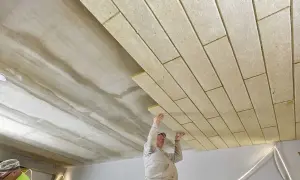 Pracownicy montują płyty izolacyjne, wykonując ocieplenie stropu betonowego.