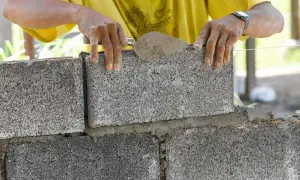 Budowniczy układa bloczek fundamentowy, dbając o jego wymiary i równość.