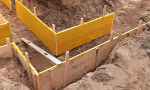Wykonano wykopy pod fundamenty. Widać drewniane szalunki i żółtą folię zabezpieczającą.