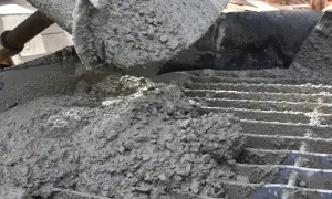 Świeży beton z kruszywem, idealny jako jaki beton pod obrzeża, wylewany na ruszt.