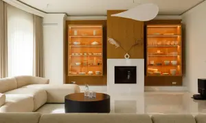 Nowoczesny salon z kominkiem, przeszklonymi witrynami i beżową sofą.