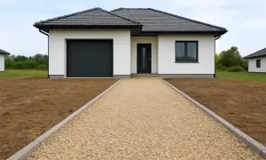 Nowy dom z garażem i wejściem wyłożonym jasnym kruszywem na podjazd.
