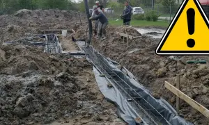 Pracownicy wylewają beton na zbrojenie, tworząc fundamenty domu. Teren budowy jest błotnisty.