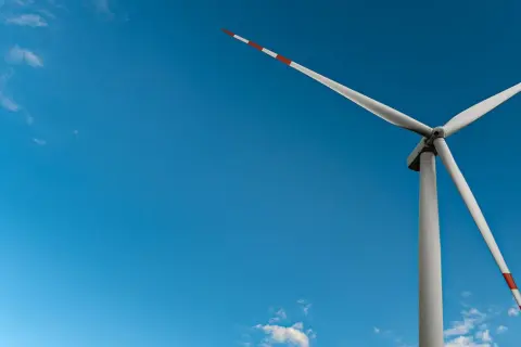 Wiatrak na tle błękitnego nieba, symbol czystej energii wiatru.