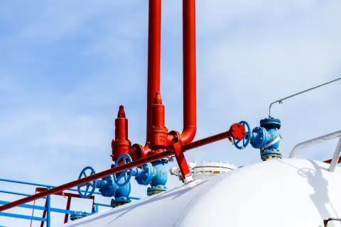 Zawory i rury na białym zbiorniku na gaz. Zastanawiasz się, na ile wystarcza zbiornik na gaz 2700?