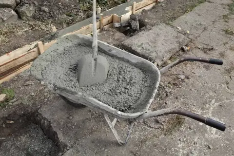 Taczka z betonem i łopatą czeka na wylanie fundamentów. Uziom fundamentowy w trakcie budowy.