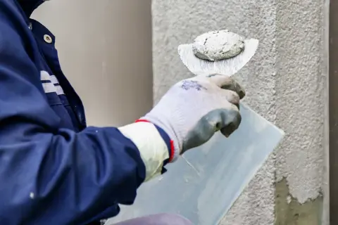 Pracownik nakłada tynk silikonowy na ścianę. Sprawdź atrakcyjną cenę za m2 robocizny.