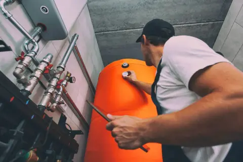 Technik sprawdza temperaturę na bojlerze, który jest częścią systemu ogrzewania gazowego.