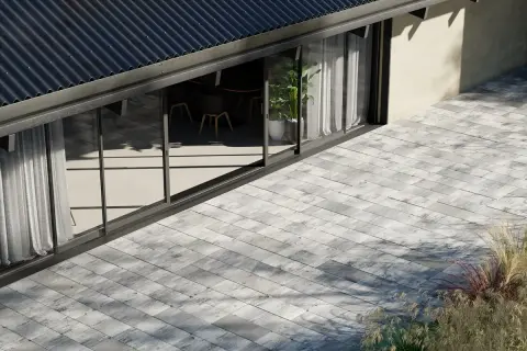 Nowoczesna kostka brukowa na tarasie przed domem z dużymi oknami.
