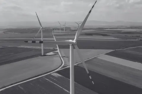 Wiatraki na tle pól i wzgórz. Nowa ustawa wiatrakowa sprzyja rozwojowi farm wiatrowych, tworząc zieloną energię.