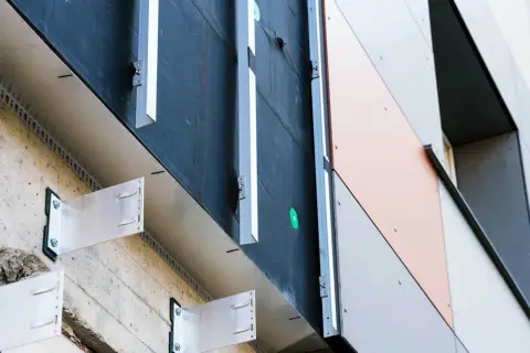 System mocowania elewacji wentylowanej z widocznymi wspornikami aluminiowymi i czarną membraną. Nowoczesne wykończenie budynku.