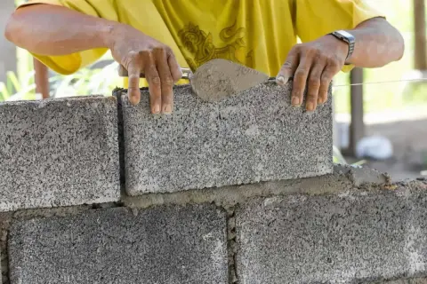 Budowniczy układa bloczek fundamentowy, dbając o jego wymiary i równość.