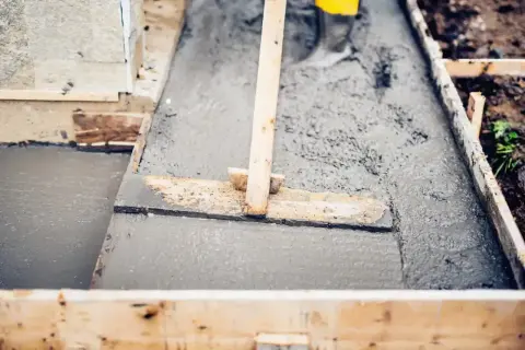 Wylewanie świeżego betonu B20 w szalunku. Sprawdzamy, czy beton b20 cena za m3 jest korzystna, by dokończyć prace.