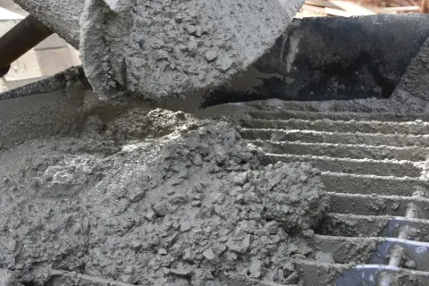 Świeży beton z kruszywem, idealny jako jaki beton pod obrzeża, wylewany na ruszt.
