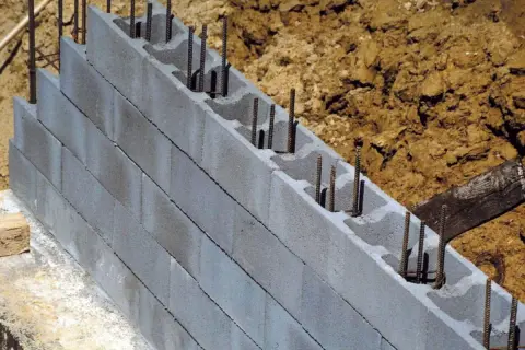 Ściana fundamentowa z pustaków betonowych z zbrojeniem, w trakcie budowy.