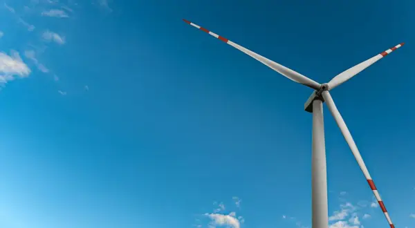 Wiatrak na tle błękitnego nieba, symbol czystej energii wiatru.