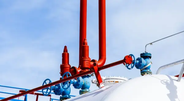 Zawory i rury na białym zbiorniku na gaz. Zastanawiasz się, na ile wystarcza zbiornik na gaz 2700?