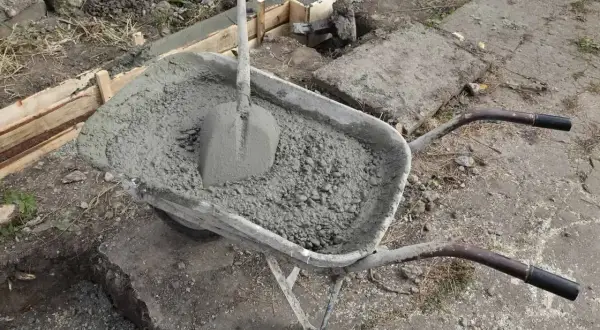 Taczka z betonem i łopatą czeka na wylanie fundamentów. Uziom fundamentowy w trakcie budowy.