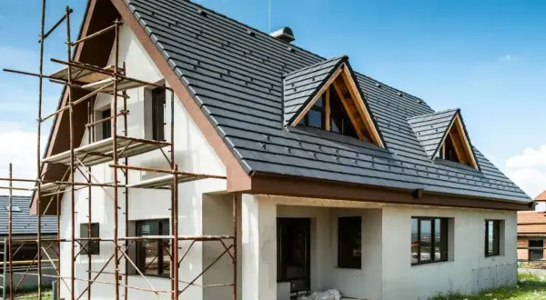 Dom w trakcie budowy, rusztowania przy ścianie. Zastanawiasz się, ile kosztuje ocieplenie domu 200m2?