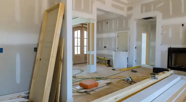 Wnętrze w trakcie przebudowy, widoczne drzwi, materiały budowlane i narzędzia.