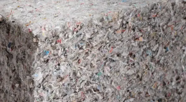 Materiały budowlane: celuloza ocieplenie z recyklingu, tworzące zwartą, włóknistą strukturę z kolorowymi fragmentami.
