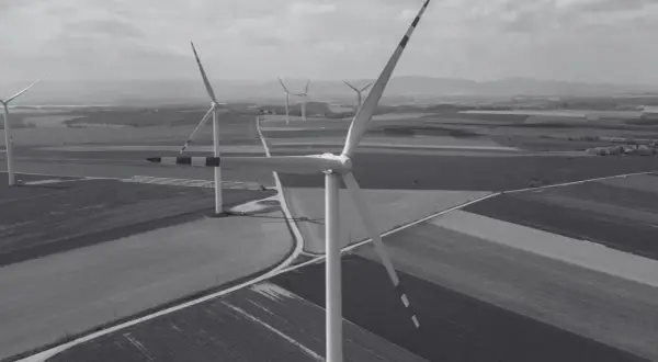 Wiatraki na tle pól i wzgórz. Nowa ustawa wiatrakowa sprzyja rozwojowi farm wiatrowych, tworząc zieloną energię.