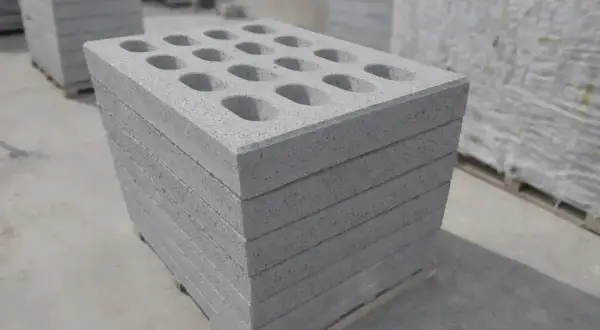 Stos betonowych pustaków z otworami na palecie.