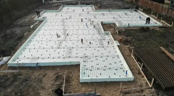 Budowa fundamentów pod dom. Widać zbrojenie i styropian, przygotowane pod szybki beton.