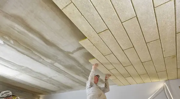 Pracownicy montują płyty izolacyjne, wykonując ocieplenie stropu betonowego.