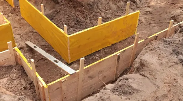 Wykonano wykopy pod fundamenty. Widać drewniane szalunki i żółtą folię zabezpieczającą.