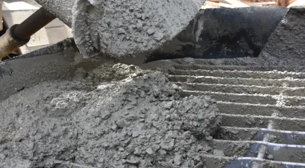 Świeży beton z kruszywem, idealny jako jaki beton pod obrzeża, wylewany na ruszt.
