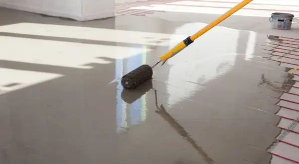 Wałek do betonu wygładza świeżą anhydryt posadzka z ogrzewaniem podłogowym.