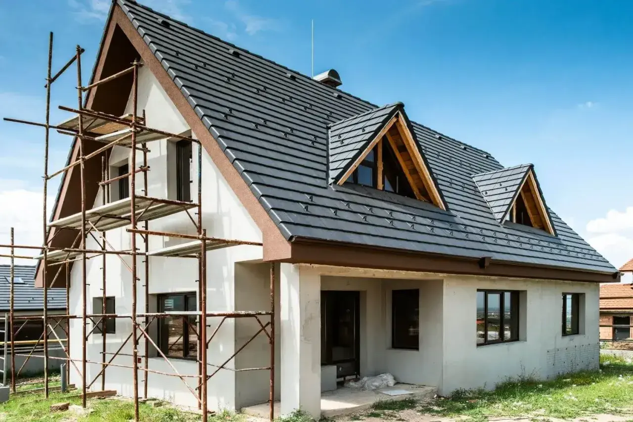 Dom w trakcie budowy, rusztowania przy ścianie. Zastanawiasz się, ile kosztuje ocieplenie domu 200m2?