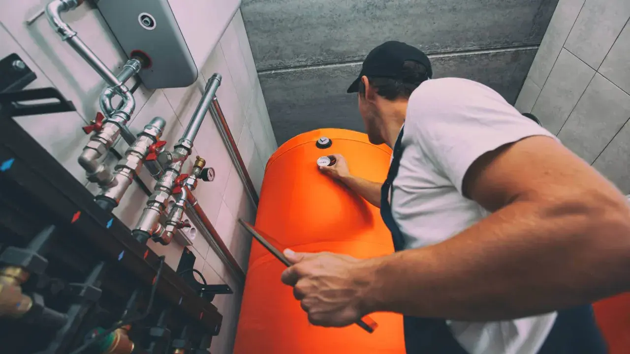 Technik sprawdza temperaturę na bojlerze, który jest częścią systemu ogrzewania gazowego.