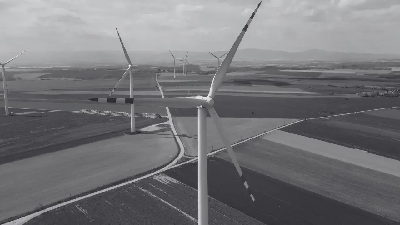 Wiatraki na tle pól i wzgórz. Nowa ustawa wiatrakowa sprzyja rozwojowi farm wiatrowych, tworząc zieloną energię.