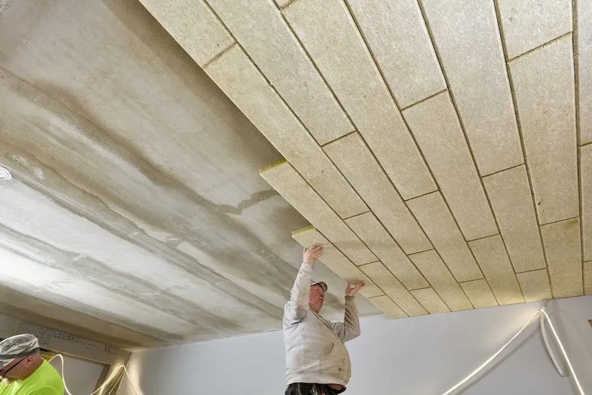 Pracownicy montują płyty izolacyjne, wykonując ocieplenie stropu betonowego.