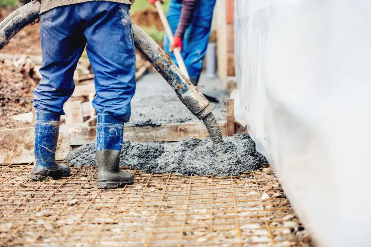 Pracownicy wylewają beton na zbrojenie. Wiedząc, ile waży kubik betonu, można oszacować ciężar tej budowy.
