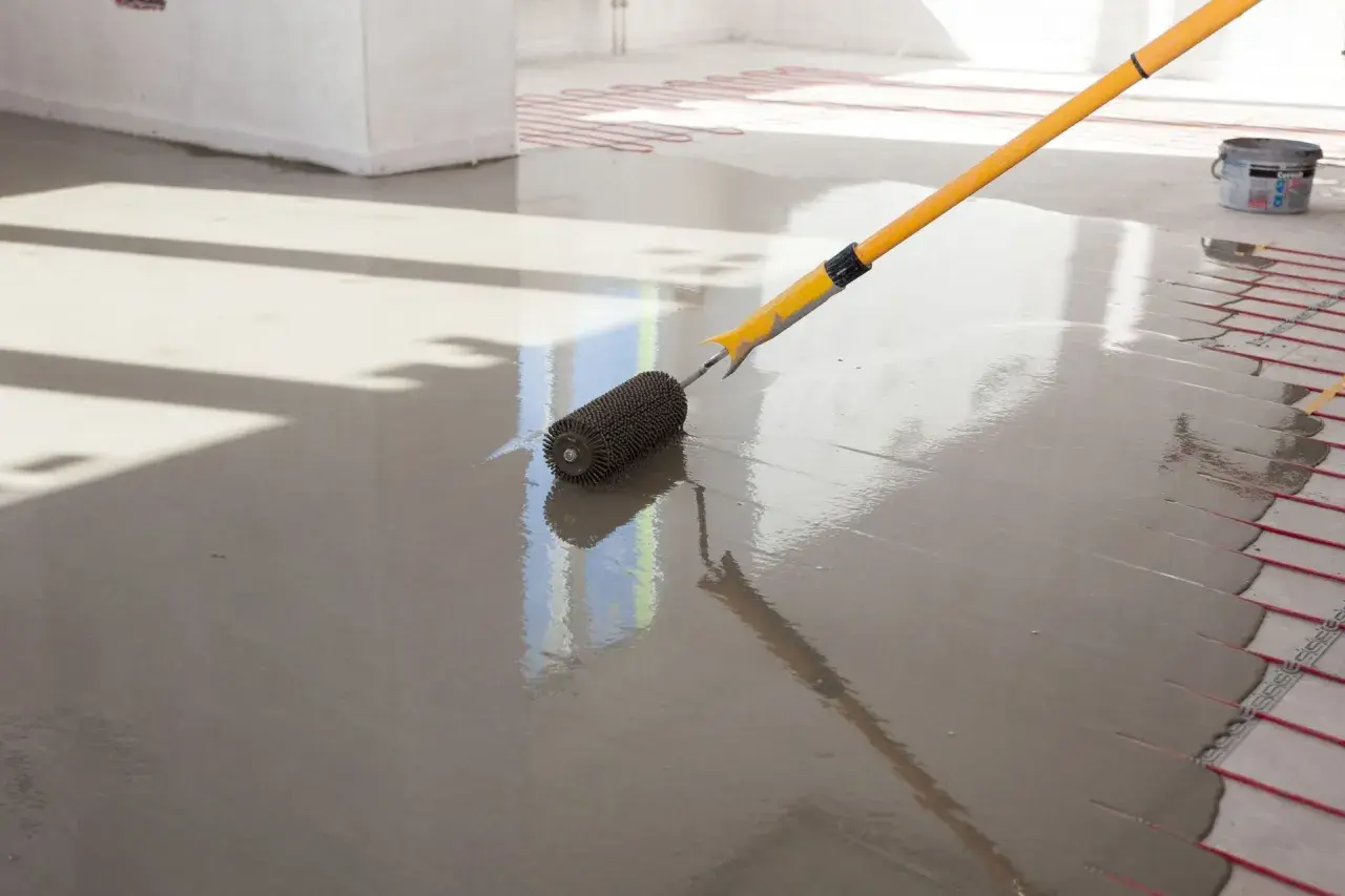Wałek do betonu wygładza świeżą anhydryt posadzka z ogrzewaniem podłogowym.